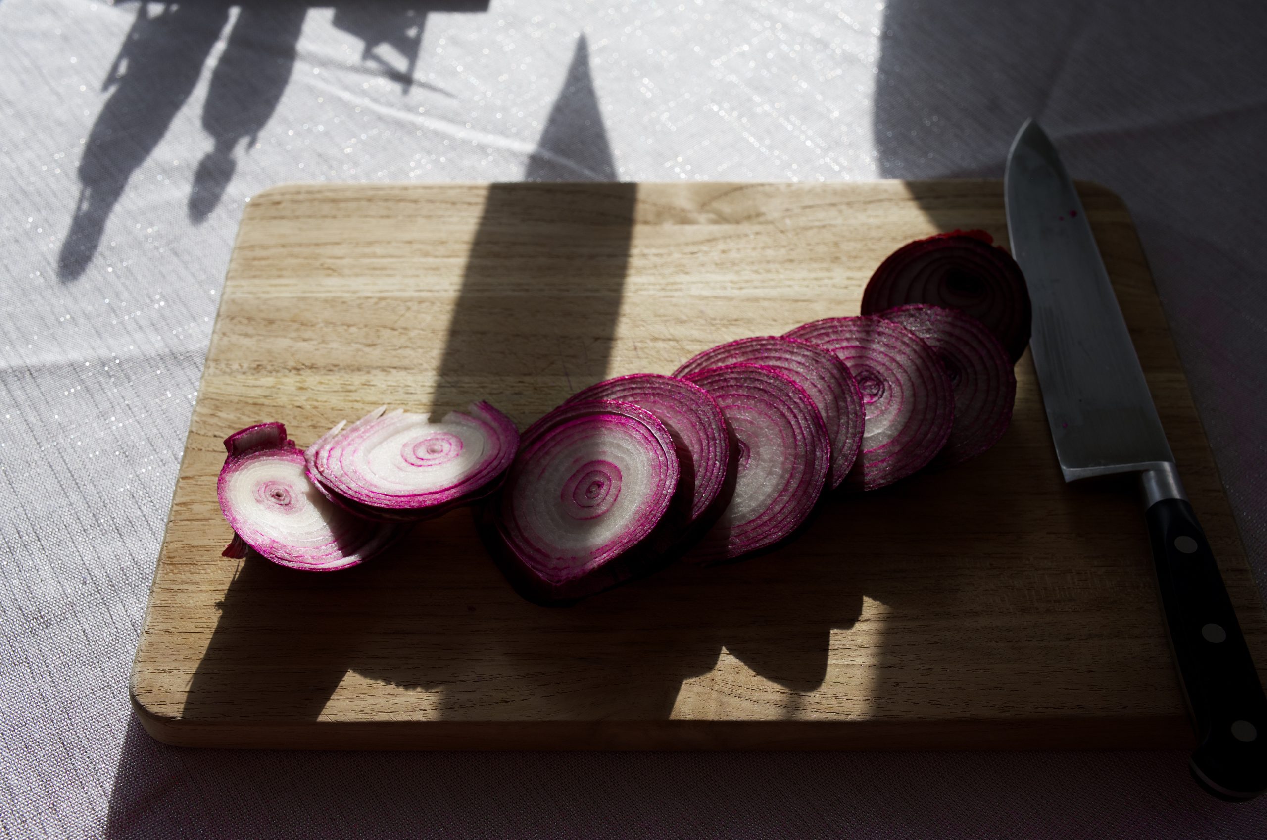 A photo of a red onion sliced on top of a cutting board.